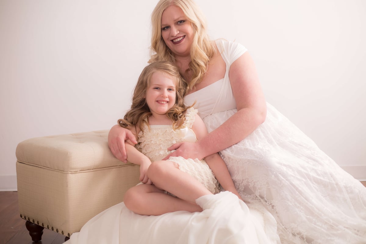 mother and daughter dressed in white smiling against a white wall