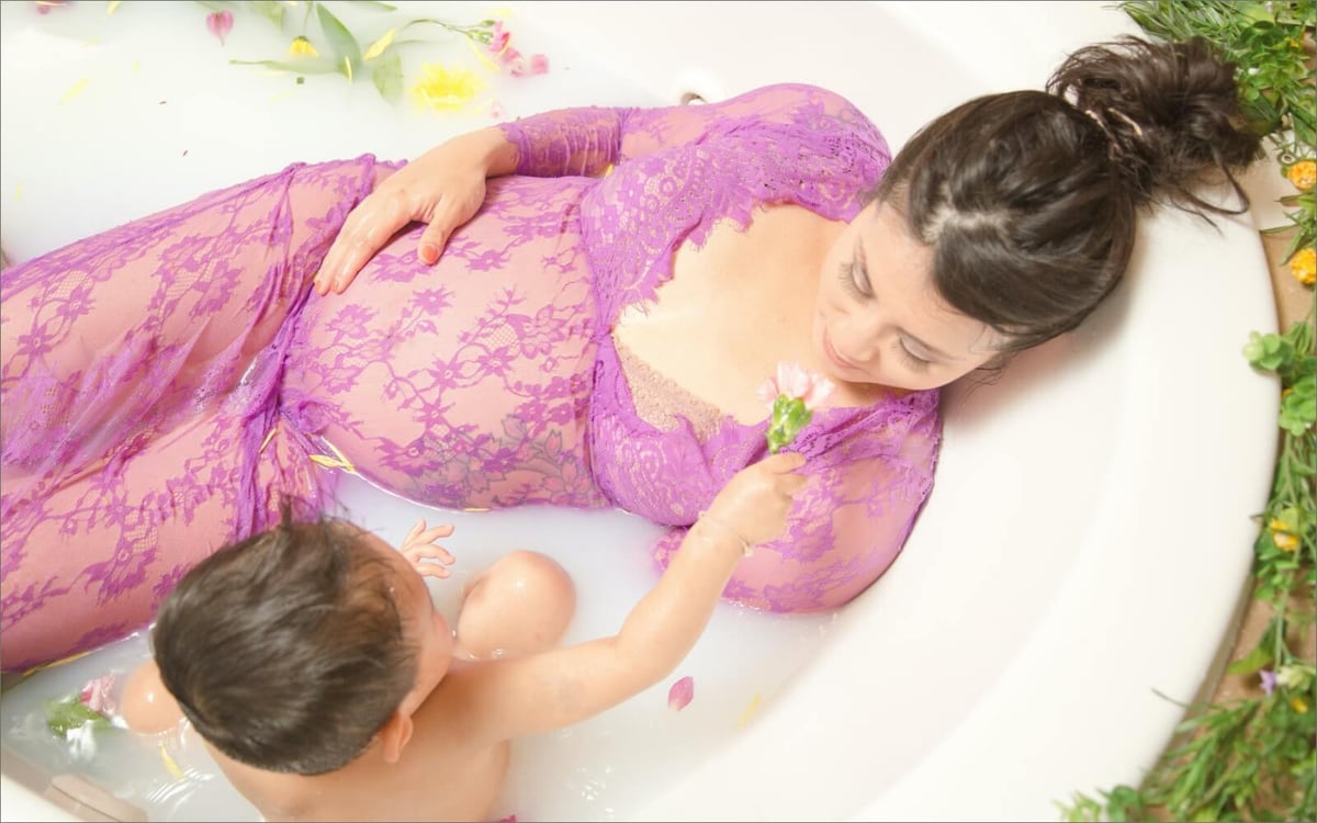 pregnant woman and baby in milk bath with flowers