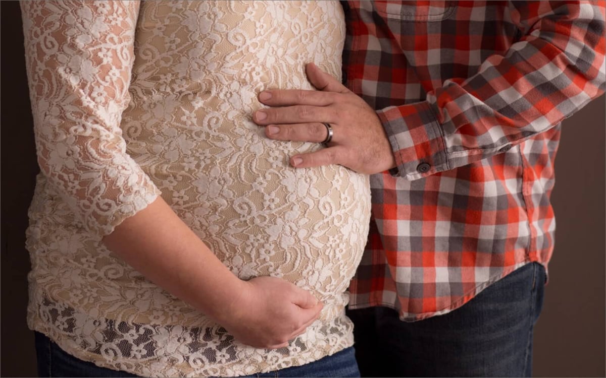 husband and wife cradling baby bump