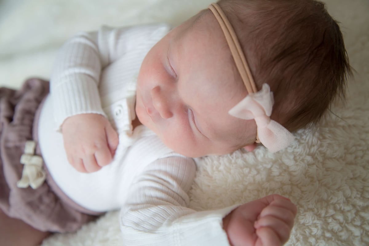 sleeping newborn girl with pink bow headband