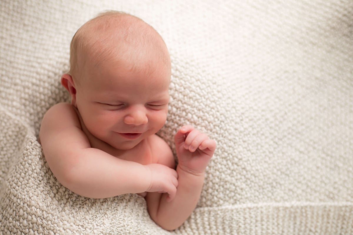 newborn boy smiling while asleep